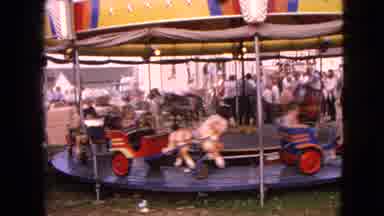 Walworth Wisconsin USA (1963): Kids Happily Riding In Little Chariots On A Merry