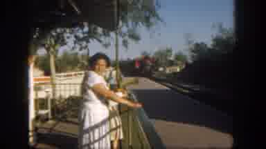 Disneyland California (1962): Woman Wearing White Dress Watches Approaching Red
