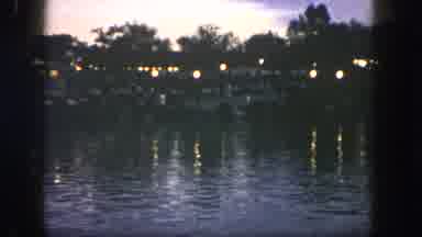 Disneyland California (1962): A Bay At Dusk With Buildings And Lights Across The