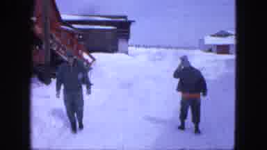 Proctor Minnesota (1963): Two Men Walk Past Red Building On A Sunny Winter Day