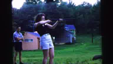 CAMDEN NEW JERSEY USA-1964: Woman Aiming Shotgun in Backyard with Pink and Blue Houses