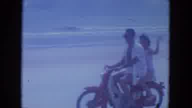 Clearwater Florida (1964): Man Riding A Red Motorcycle On A Beach With A Woman On