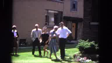 Evanston Illinois (1964): Black Dog And People Walking On Green Grass On A Bright