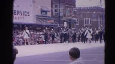 Harvard Illinois USA (1964): Marching Band Walking Down The Street As A Crowd