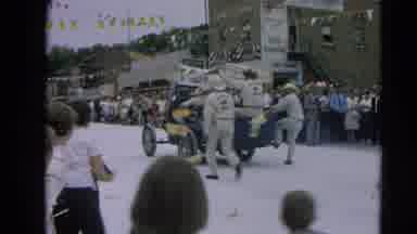 Harvard Illinois USA (1964): Men In An Old Car In A Parade Throw Treats To