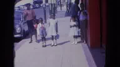 KINGSTON JAMAICA-1964: Three Children Standing in Sunlight Near Woman Under Umbrella