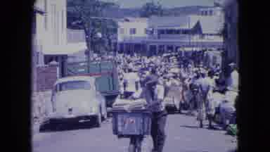 Kingston Jamaica (1964): Man Pushing His Bike With Baggage Away From A Crowded