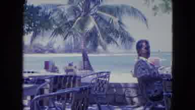 KINGSTON JAMAICA-1964: An Older Gentleman Is Sitting All By Himself On A Beachside Cafe