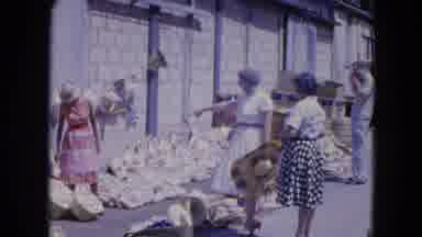 Kingston Jamaica (1964): Woman Holding Tan Sombrero Points At Object At Outdoor