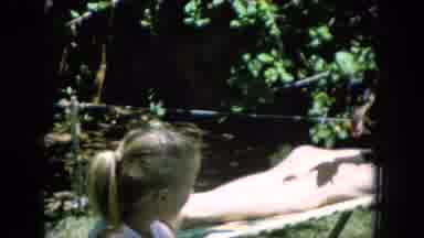 Oahi Hawaii (1964): Black Dog Sits In Lap Of Man Wearing Black Shorts Sitting In
