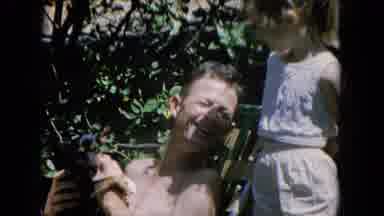 Oahi Hawaii (1964): Father Plays With Puppy As He Sits In Lawn Chair While Little