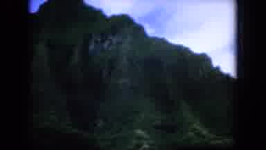 Oahi Hawaii (1964): Long Shot Of Green Mountains And Cars Driving Down Highway