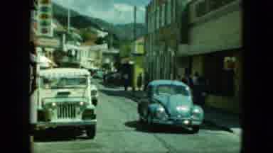 Saint Thomas (1964): Light Blue Volkswagen Beetle Drives Down Narrow City Street