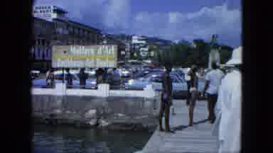 USA Virgin Islands (1964): Primarily Black Men Gather On Street By Canal Of