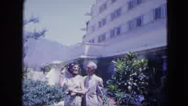 VENEZULA-1964: Man And Lady Posing Outside Tropical Hotel With Mountains