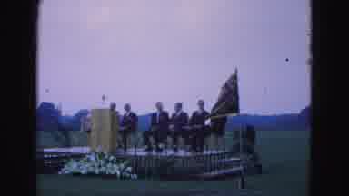 Williamsburg Virginia USA (1964): Men Sit On A Stage Beside A Podium And A Flag