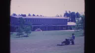 Williamsburg Virginia USA (1964): A Man On A Lawn Mower With A Giant Building In