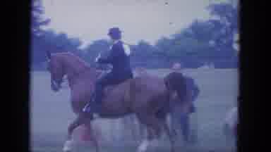 Louisville Kentucky USA (1965): A Jockey On Top Of A Horse Trotting Past Ongoing