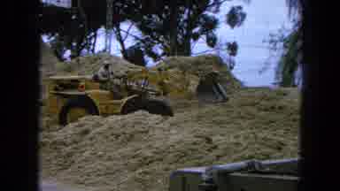 Pueblo Mexico (1965): Man Driving In A Yellow Digger Is Reversing Fast Through A