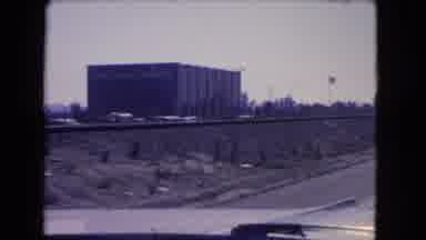 California USA (1966): Driving Past A Black Building On The Freeway Along With