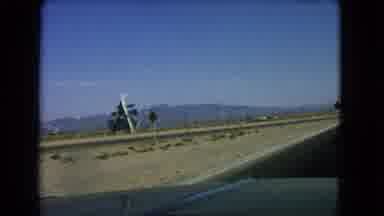 Las Vegas Nevada (1966): Vehicle Travels Road In Arid Geography Past Large