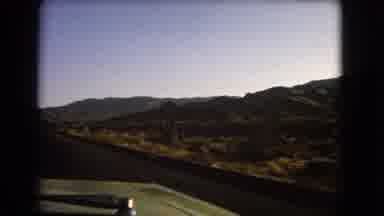 Nevada USA (1966): An Automobile Drives Down A Road In The High Desert In
