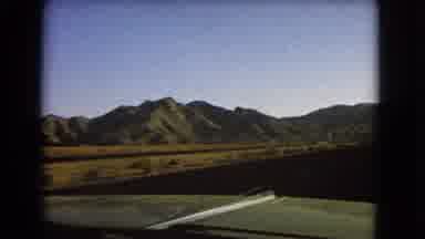 Nevada USA (1966): Mountains From Green Car Driving On Open Flat Road With Bushes