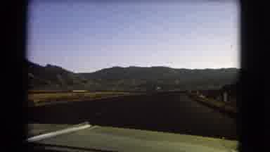 Nevada USA (1966): A Car Drives Down The Road With Mountains On Either Side