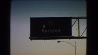 Nevada USA (1966): Driving Past And Old Town And A Freeway Sign For Barstow