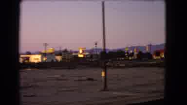 Nevada USA (1966): A Vehicle Drives Down The Road With A View Of A Town In The