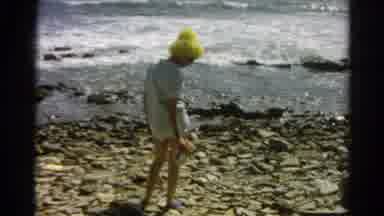 Silver Lake California (1966): Woman Wearing Yellow Hat Picks Up Object From