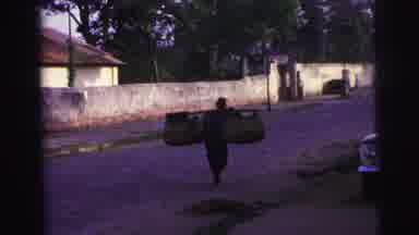 Brazil (1967): A Man Walks Down A Road With A Pole And Two Large Baskets Across