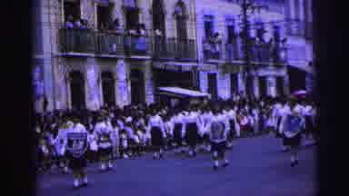 Brazil (1967): Girls March In Street Wearing Shields Past A Line Of Apartments