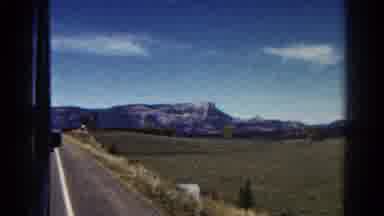 Colorado US (1967): Driving Past An Open Field Of Green And Mountains In The