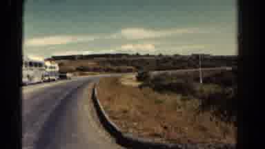 Colorado US (1967): Buses Are Parked By A Paved Road With Green Shrubs On Either