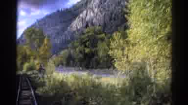 Colorado USA (1967): The Train Is Moving Alongside A Rocky River Bank