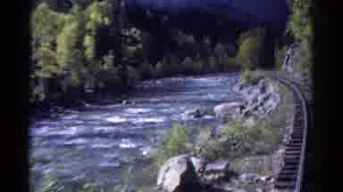 Colorado USA (1967): Train Moving Along Train Tracks Near River Rapids And Woods