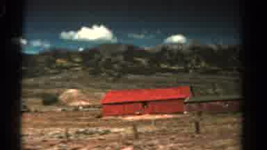 Colorado USA (1967): Driving Past A Couple Of Red Buildings With Mountains And Big