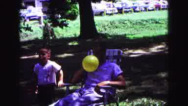 Galena Illinois USA (1967): Father Blowing Up Colorful Balloons While Sitting For
