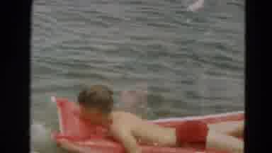 Minnesota US (1967): Little Boy In Red Trunks Floats And Paddles While Lying On An