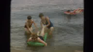 Minnesota US (1967): Girls Helping Person Get On A Floating Mat In A Lake Near