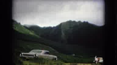 New Mexico USA (1967): Two Cars Parked Next To Green And Flowering Mountains On A