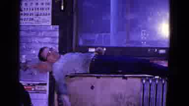Trenton New Jersey (1967): Man Resting On Box And Moving Arms Around Waving To