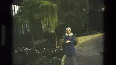 Iran (1972): A Lady In A Blue Coat And White Hat Stands On A Pathway