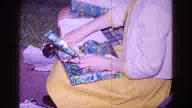 Minnesota USA (1968): A Girl Is Opening A Wrapped Present While Wearing A Yellow