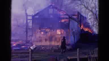 Wauconda Illinois USA (1968): Person Walking By A House On Fire And Smoking Near