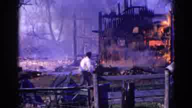 Wauconda Illinois USA (1968): A Man Walks Past A Burning Building As Firefighters