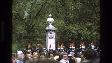 England (1969): Soldiers Marching Behind Crowd By Monuments Onlooking By A Grove