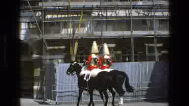 England (1969): Two People In Red Coats And Gold Conical Hats Ride Black Horses In