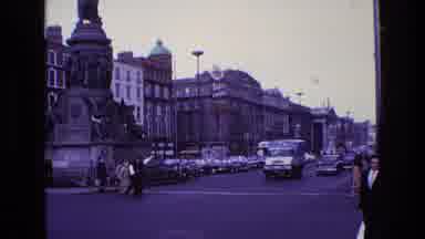 Ireland (1969): Woman Wearing Brown Coat Runs Across Crosswalk On A Clear Day
